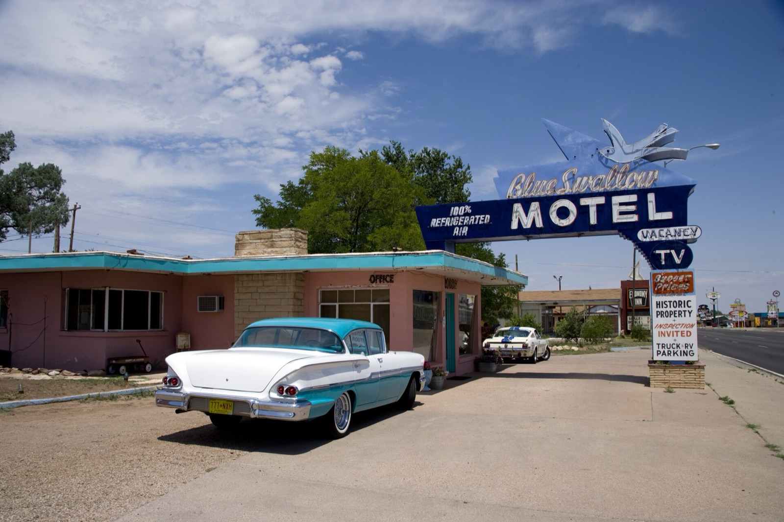 Blue Swallow Motel neon sign and pink office with a vintage two-tone sedan parked in front, Tucumcari, New Mexico