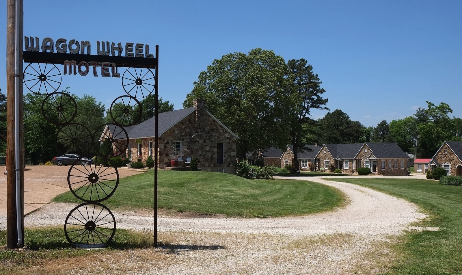 Stone cottages of the Wagon Wheel Motel behind its wagon-wheel sign in Cuba, Missouri