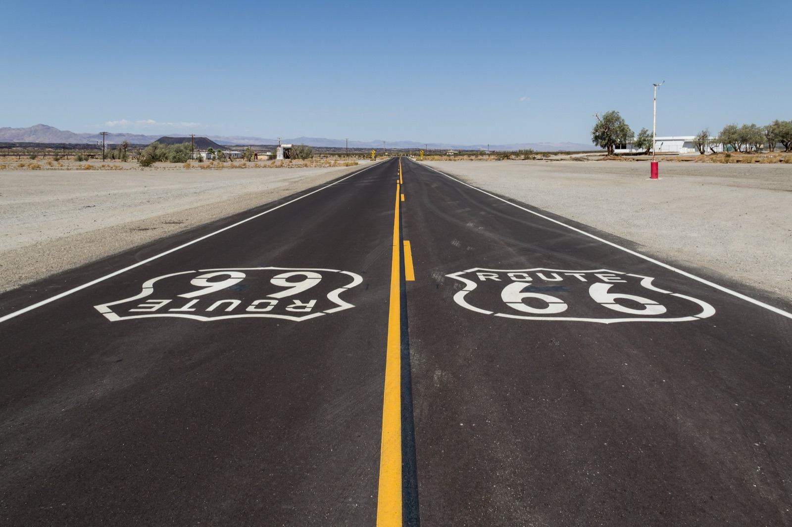 Old Route 66 near Amboy, California, a straight two-lane road with Route 66 shields painted on the asphalt running toward the desert horizon