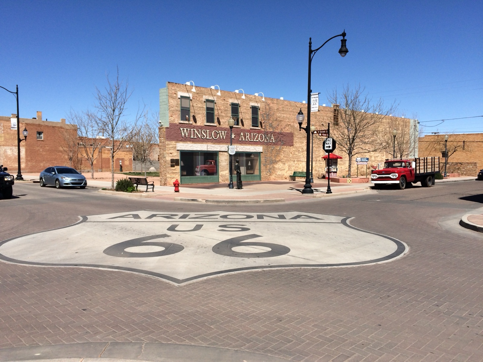 Arizona US 66 shield painted on the brick street at Standin' on the Corner Park in Winslow, Arizona, with a red vintage flatbed truck parked nearby