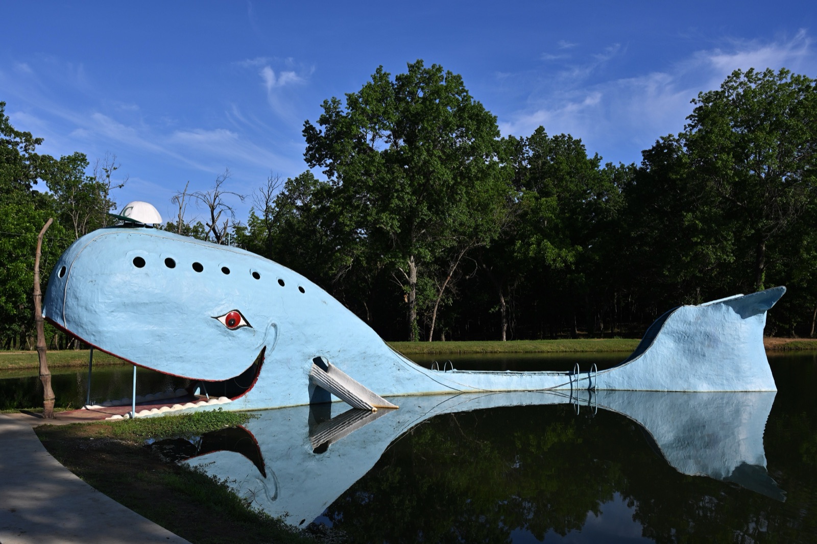 The Blue Whale of Catoosa, a smiling light-blue concrete whale in a pond surrounded by green trees, on Route 66 in Oklahoma