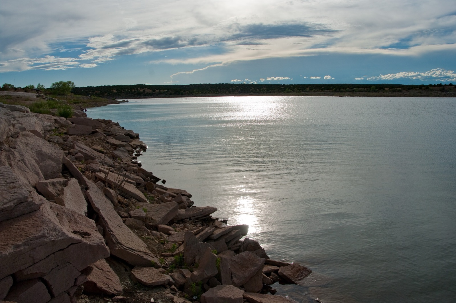 Santa Rosa Lake in New Mexico at evening, with red rock along the shore and sunlight on the water