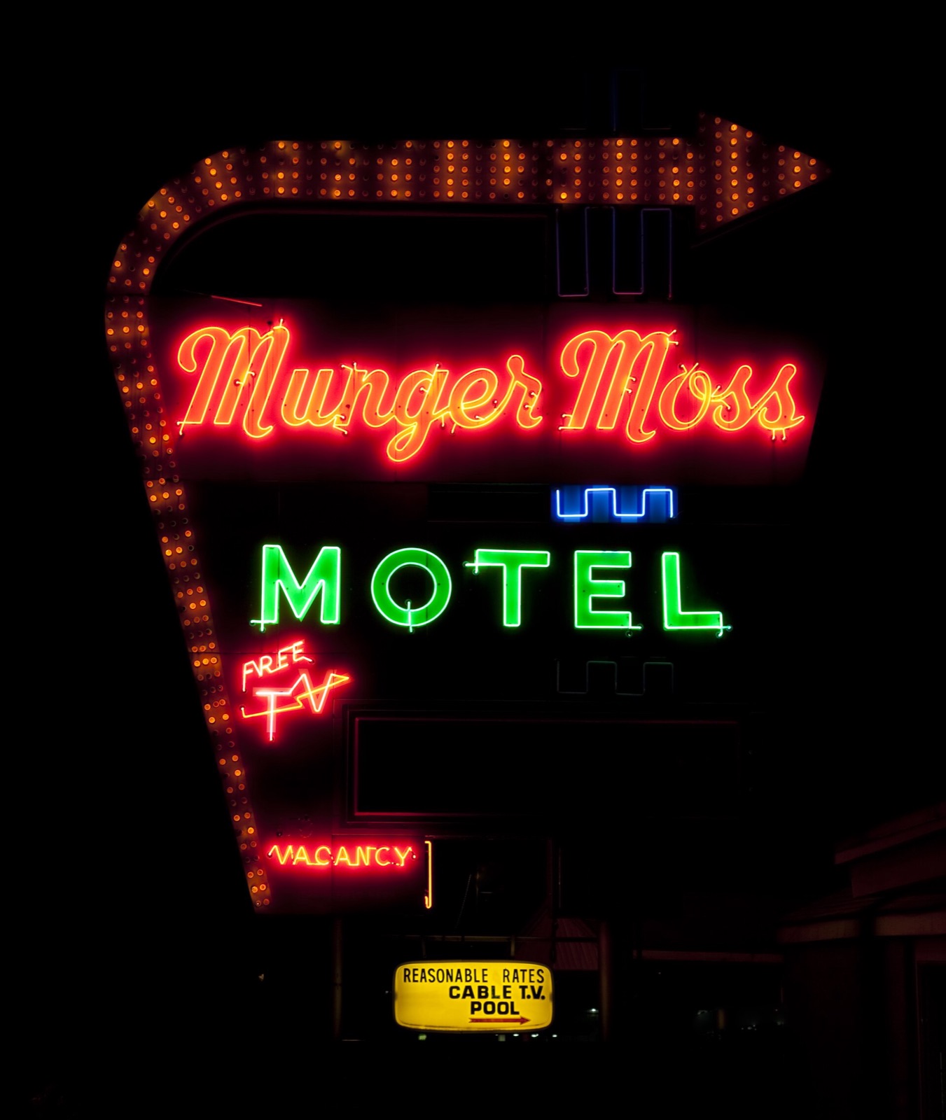 The neon sign of the Munger Moss Motel glowing red and green at night in Lebanon, Missouri