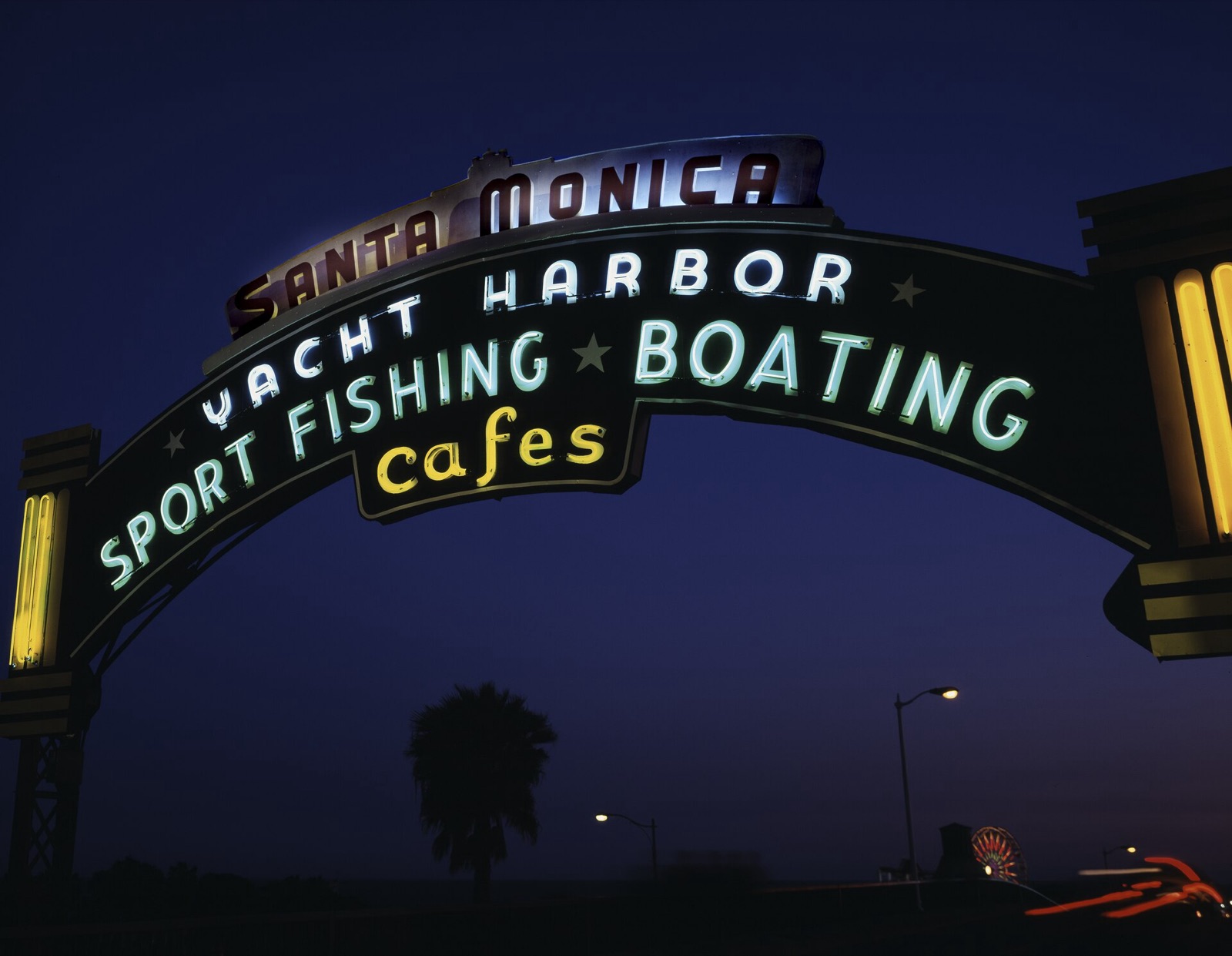 The lighted neon arch at the entrance to the Santa Monica Pier at night