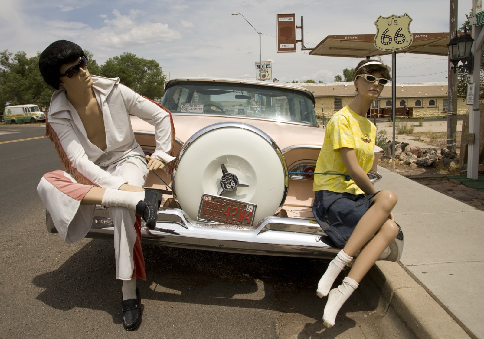 Mannequins posed beside a pink classic car under a Route 66 shield outside a souvenir store in Seligman, Arizona