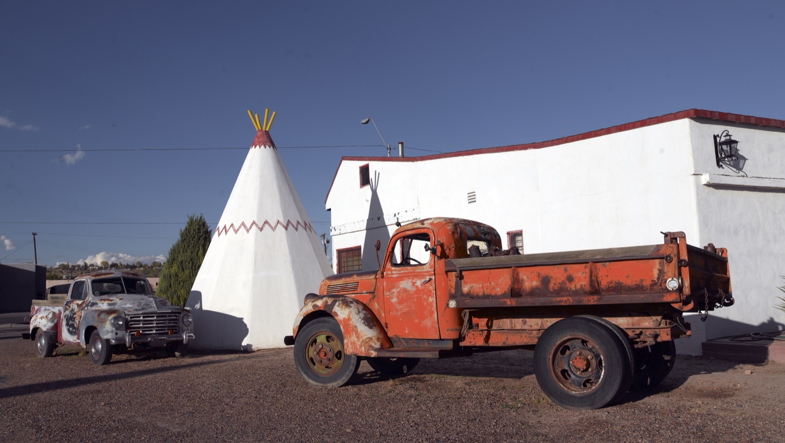 A white concrete teepee and a rusted orange vintage truck at the Wigwam Motel in Holbrook, Arizona