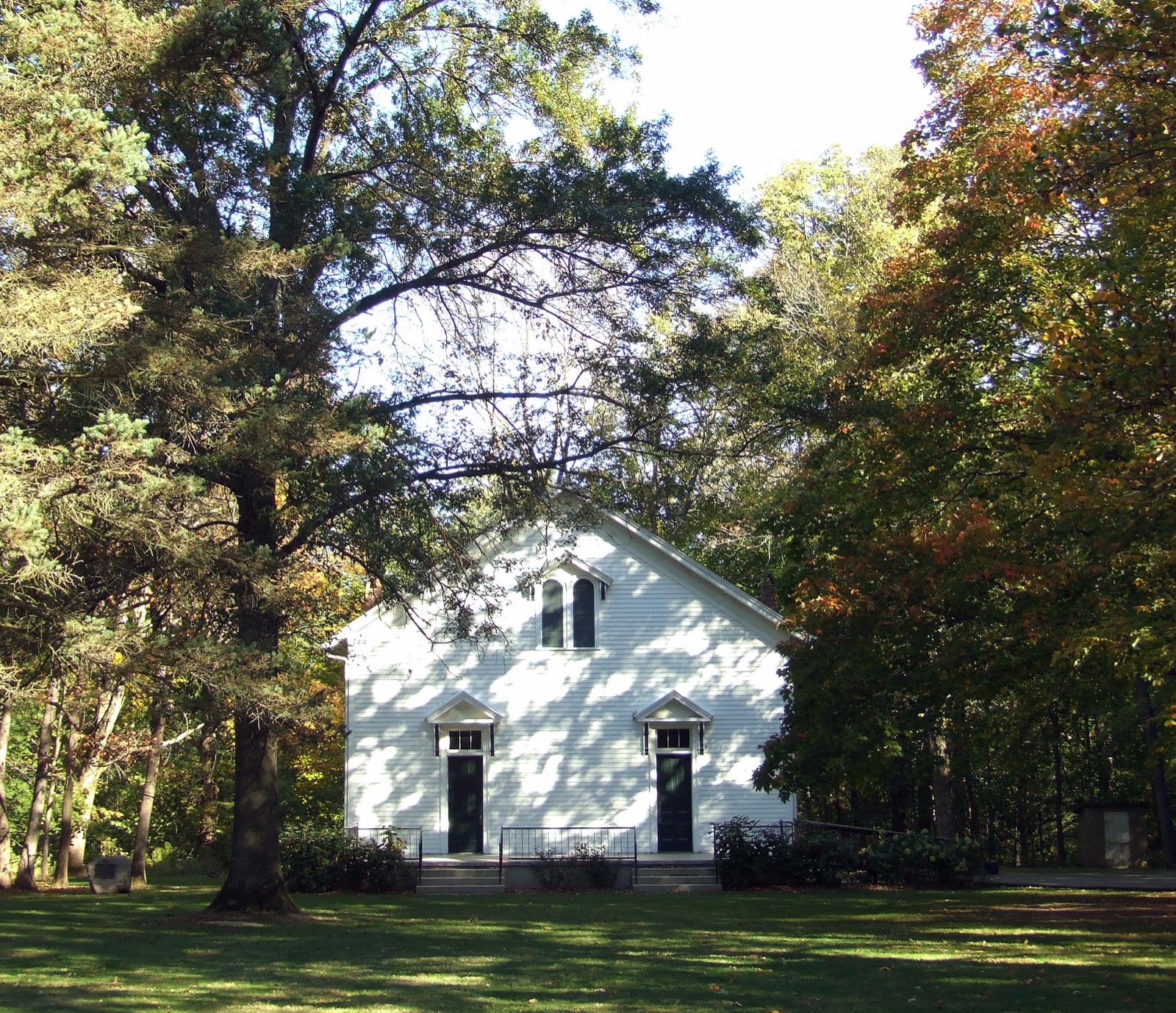White wooden Funks Grove chapel framed by trees beginning to turn orange in October