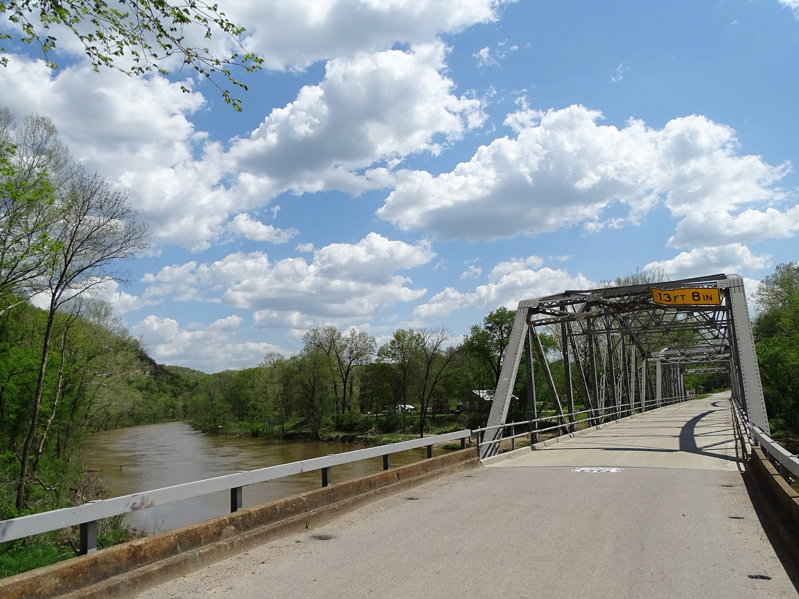 Narrow concrete deck of the Devils Elbow steel truss bridge on old Route 66 over the Big Piney River in Missouri, with spring trees along the water