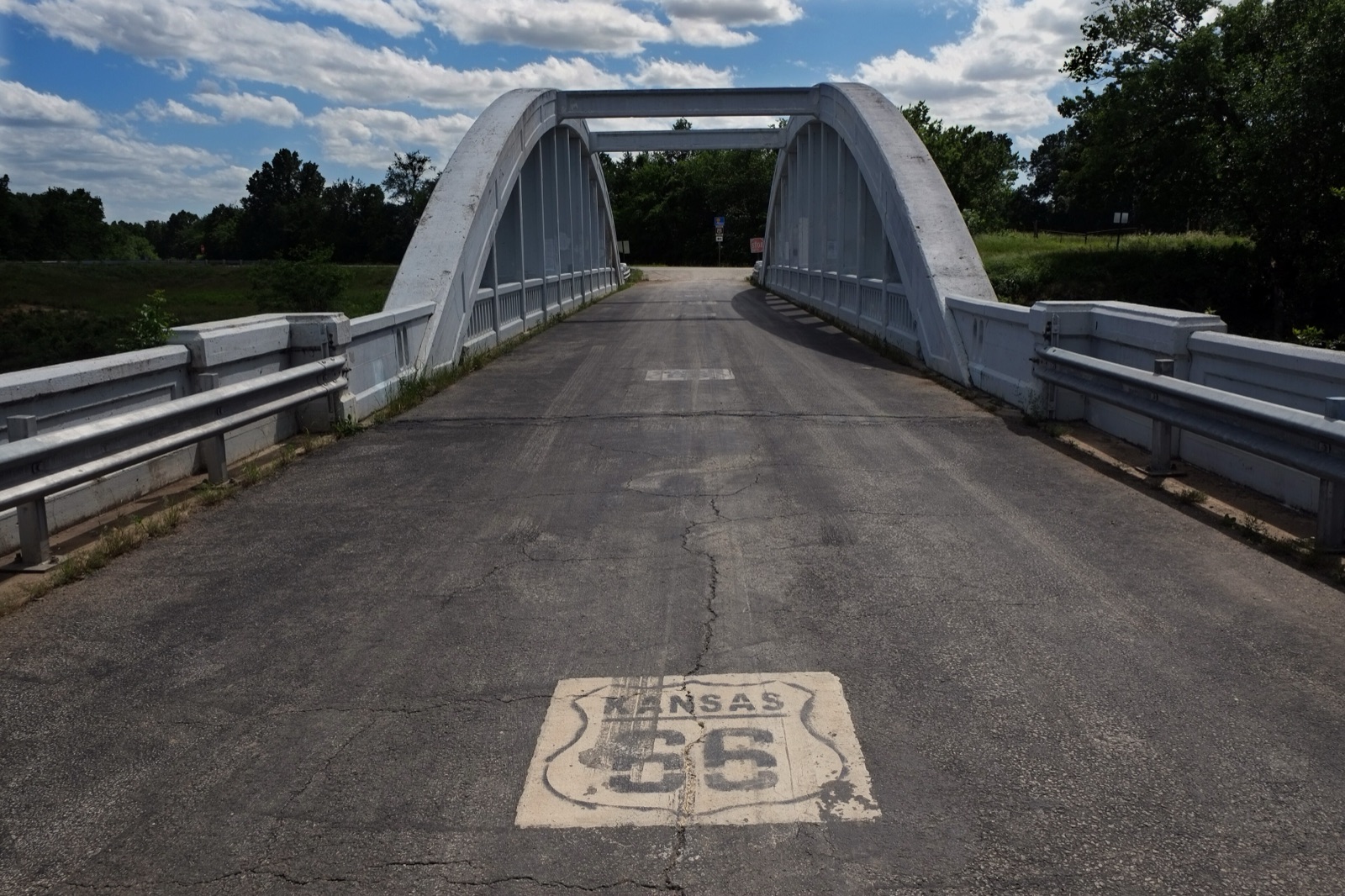The white concrete Rainbow Bridge over Brush Creek near Riverton, Kansas, with a Kansas Route 66 shield painted on the road