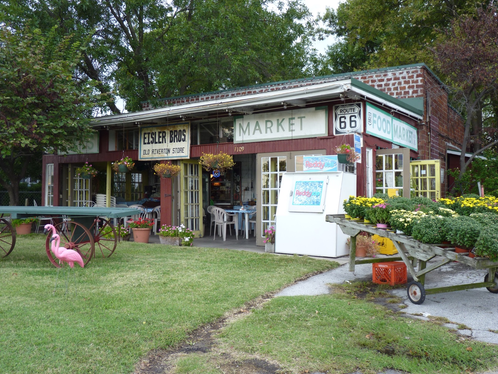 The Old Riverton Store in Riverton, Kansas, with an Eisler Bros sign, a Route 66 shield, flowers and a pink flamingo out front