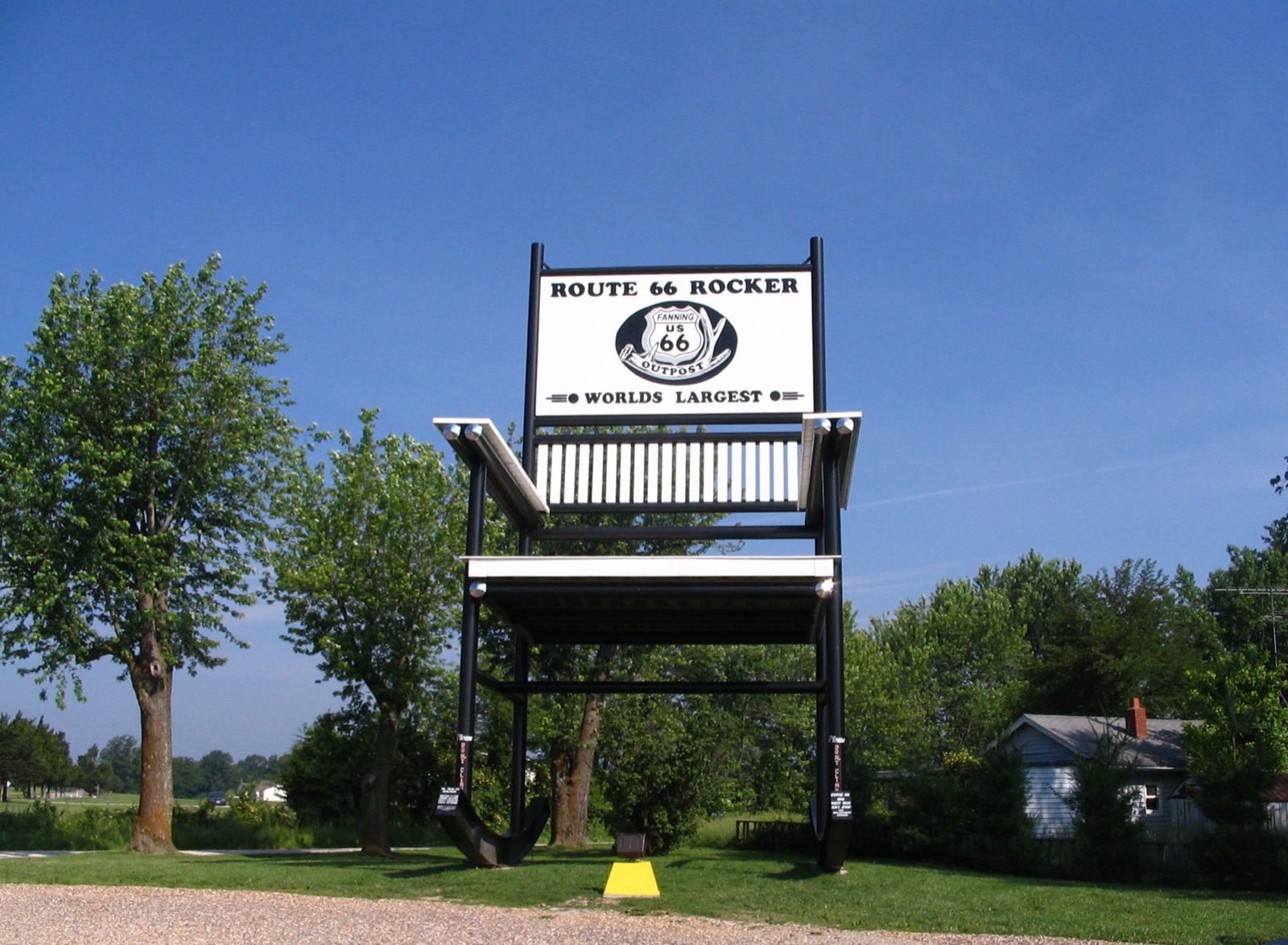 The giant black steel rocking chair at Fanning, Missouri, with a Route 66 Rocker World's Largest sign on top, under a blue sky