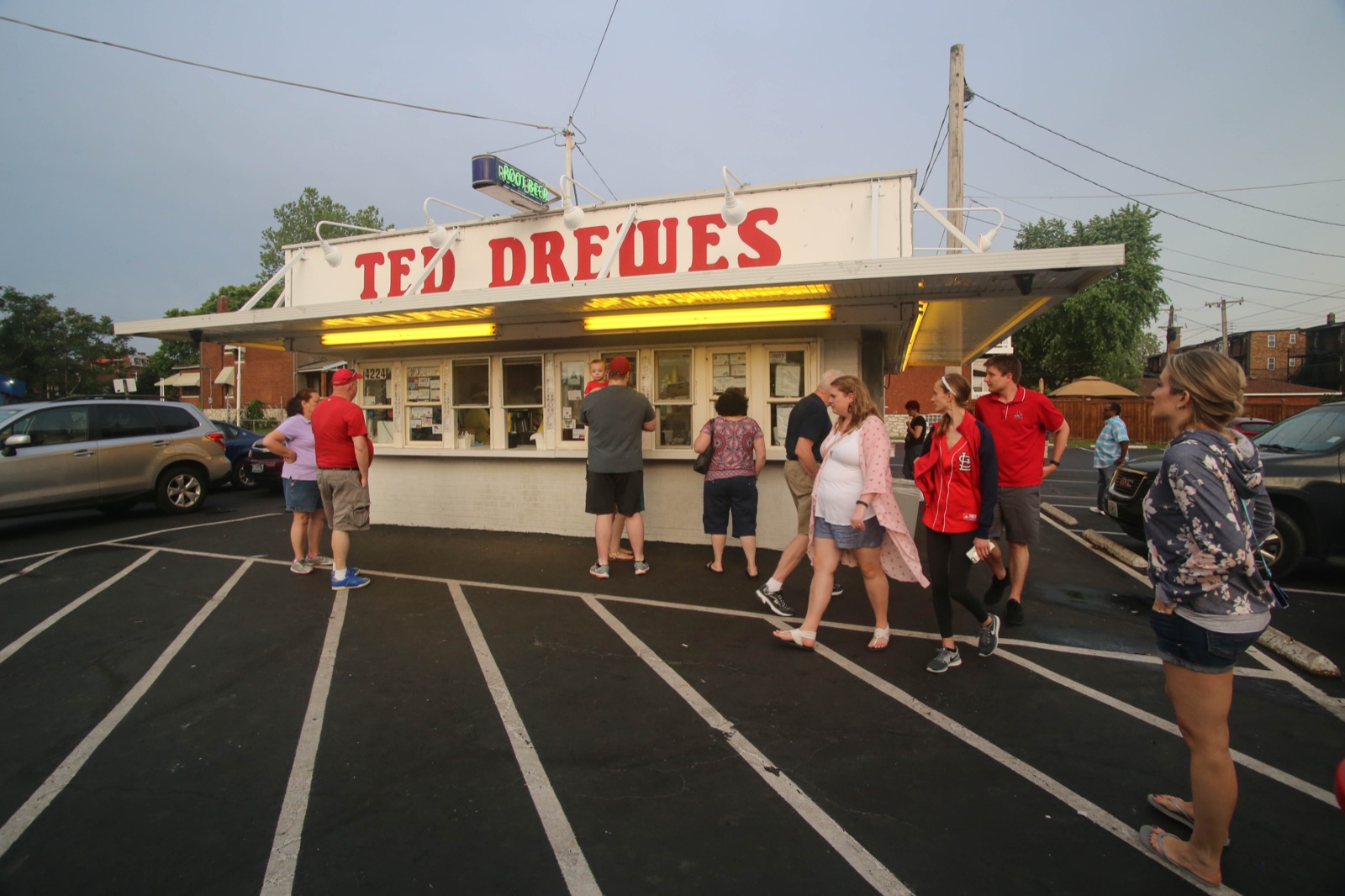 Customers lining up at the white Ted Drewes Frozen Custard stand with its red lettered sign on Chippewa Street, St. Louis, on a summer evening