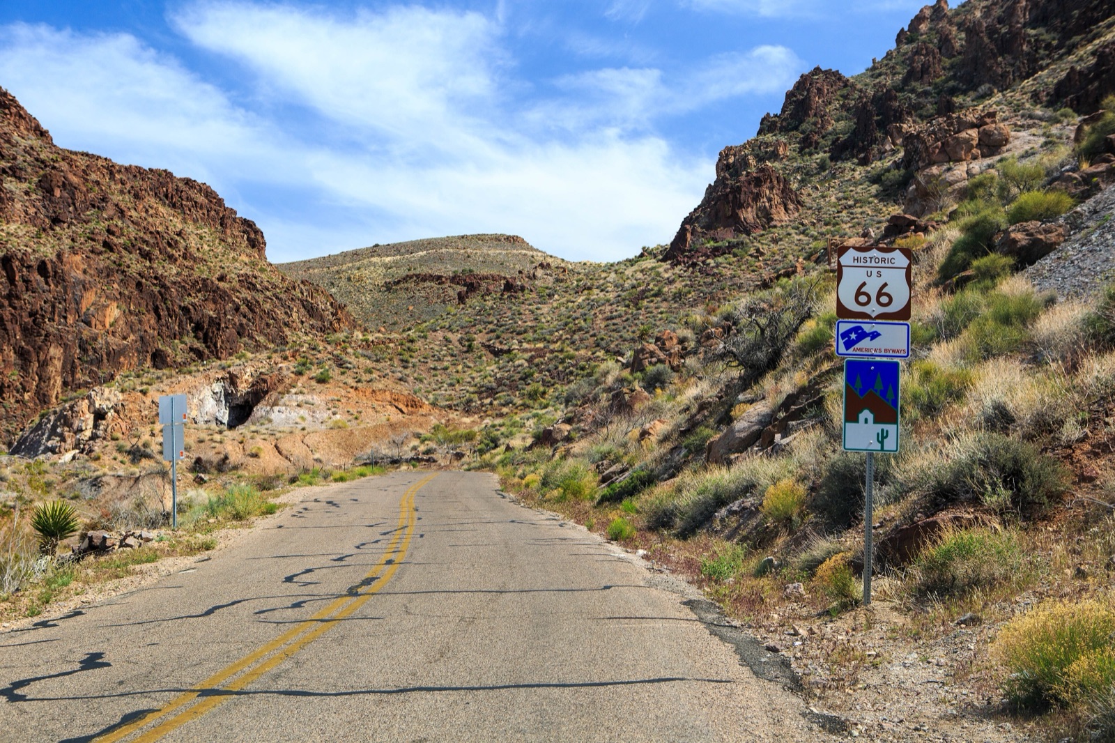 Narrow two-lane Route 66 curving through rocky hills toward Sitgreaves Pass, with a Historic Route 66 sign on the right