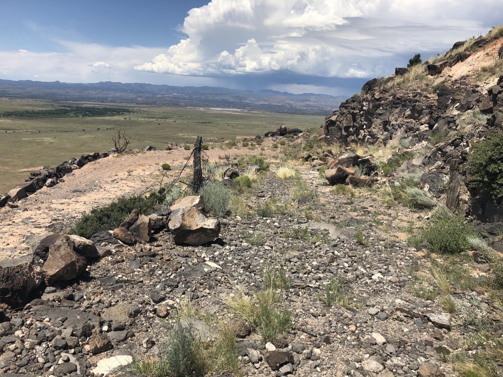 Rocky remains of a switchback on La Bajada Hill near Santa Fe, New Mexico, with the plains and storm clouds below