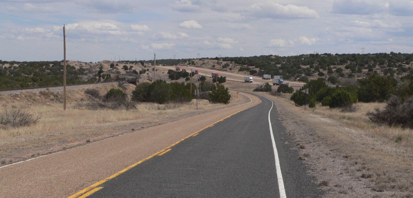 Old Route 66 as a two-lane frontage road east of Cuervo, New Mexico, with trucks on I-40 alongside