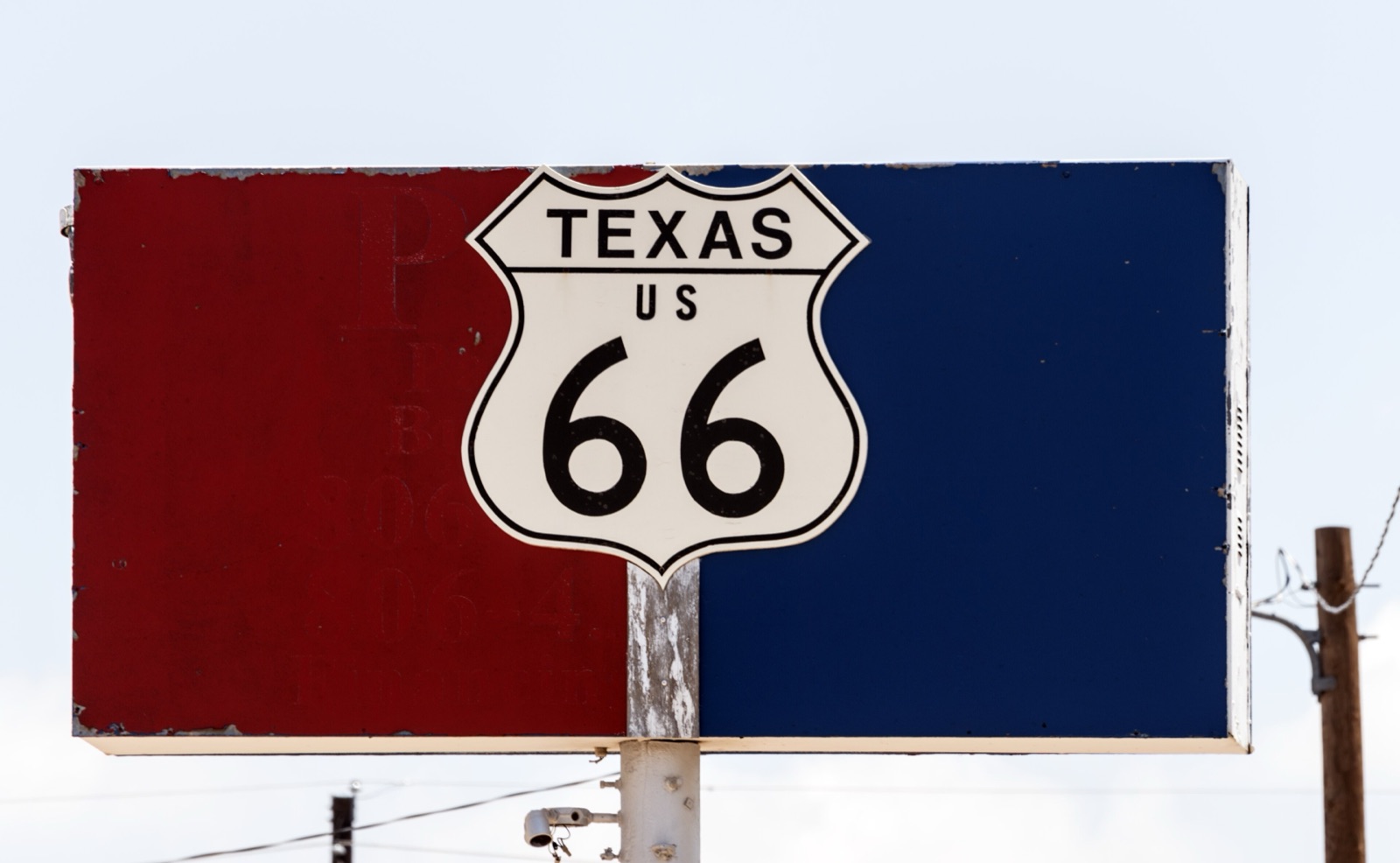 Texas US 66 highway shield mounted on a faded red and blue sign in Amarillo, Texas