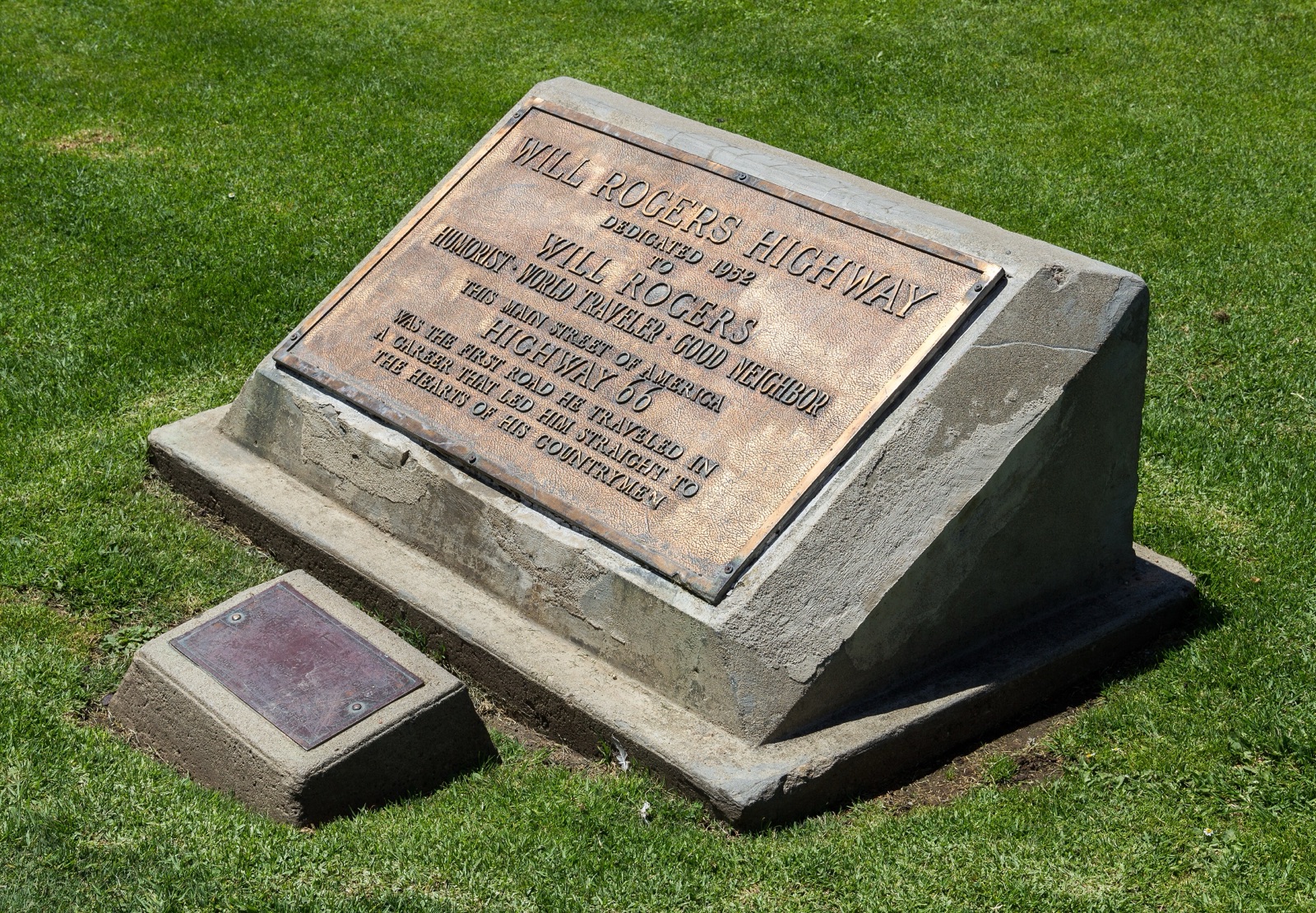 Bronze Will Rogers Highway plaque dedicated in 1952, set in a concrete block on the grass of Palisades Park in Santa Monica